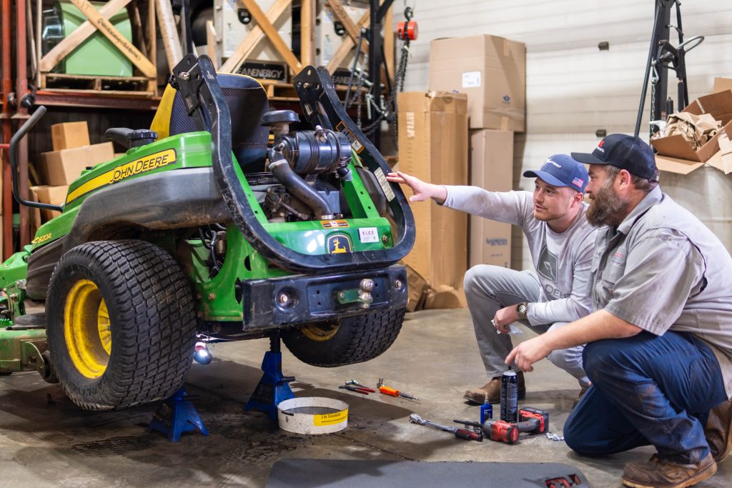 two employees discussing a lawnmower