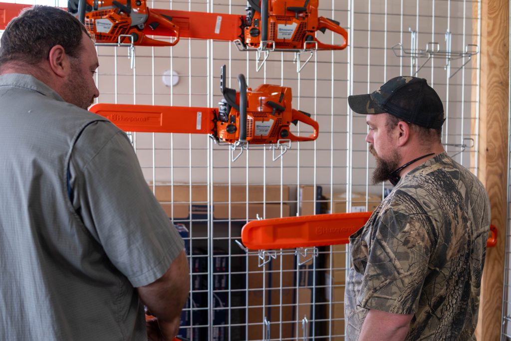 employee and customer looking at Husqvarna chainsaws